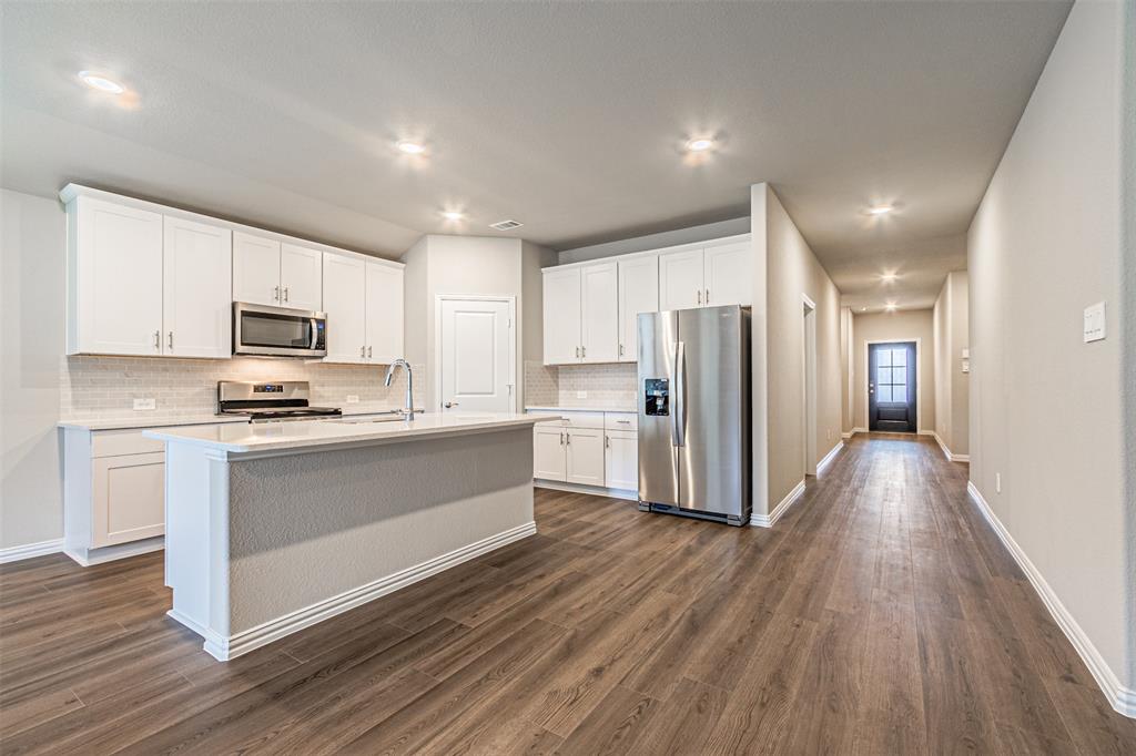 780 Moonlight Place Lavon, TX 75166 - Photo 17 of 35 Kitchen with stainless steel appliances, white cabinets, a kitchen island with sink, dark wood-style flooring, and decorative backsplash