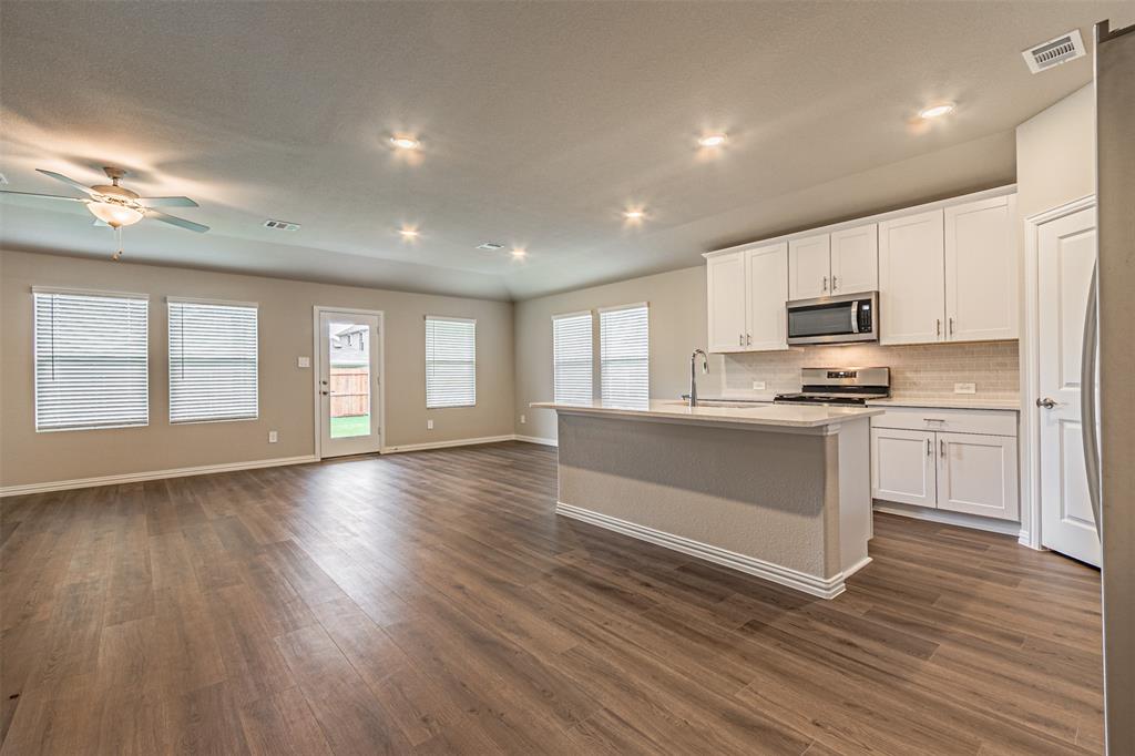 780 Moonlight Place Lavon, TX 75166 - Photo 34 of 35 Kitchen featuring white cabinets, open floor plan, an island with sink, stainless steel appliances, and dark wood-style floors