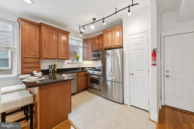 a kitchen with stainless steel appliances granite countertop a refrigerator a sink dishwasher a stove and a refrigerator