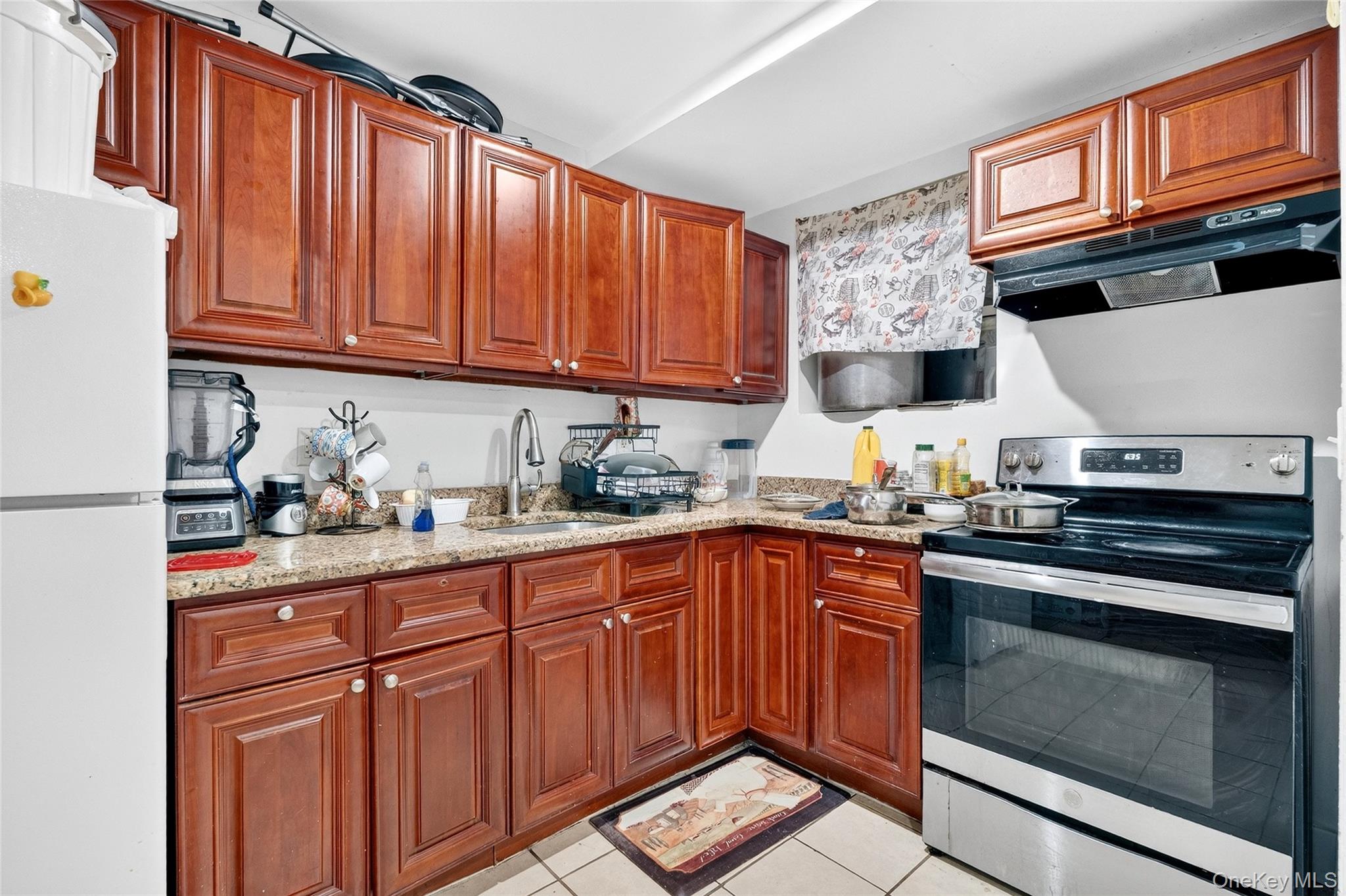 1459 Rosedale Avenue Bronx, NY 10460 - Photo 32 of 37 Kitchen featuring stainless steel electric range, freestanding refrigerator, range hood, light stone counters, and light tile patterned floors