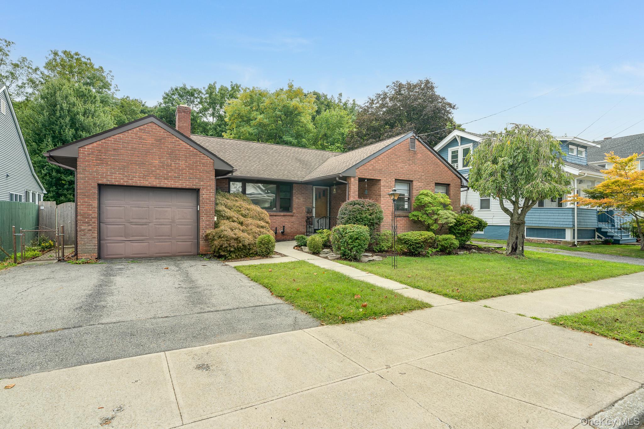 Ranch-style house with driveway, brick siding, a chimney, a garage, and roof with shingles