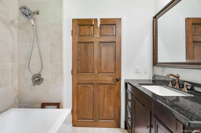 a bathroom with a granite countertop sink a mirror and a bathtub