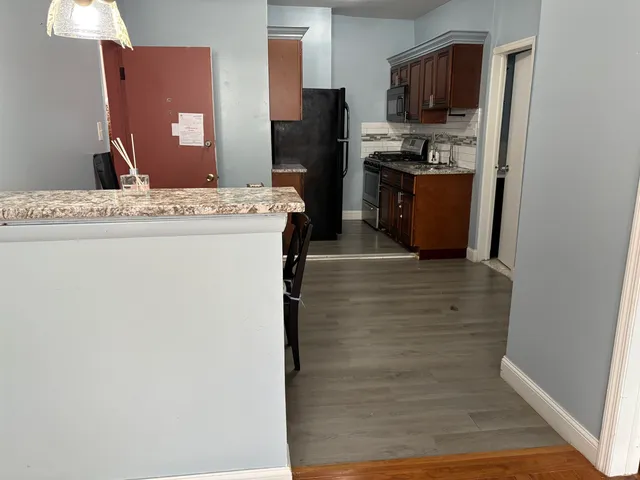 a hall with kitchen island a stove a refrigerator and a cabinets