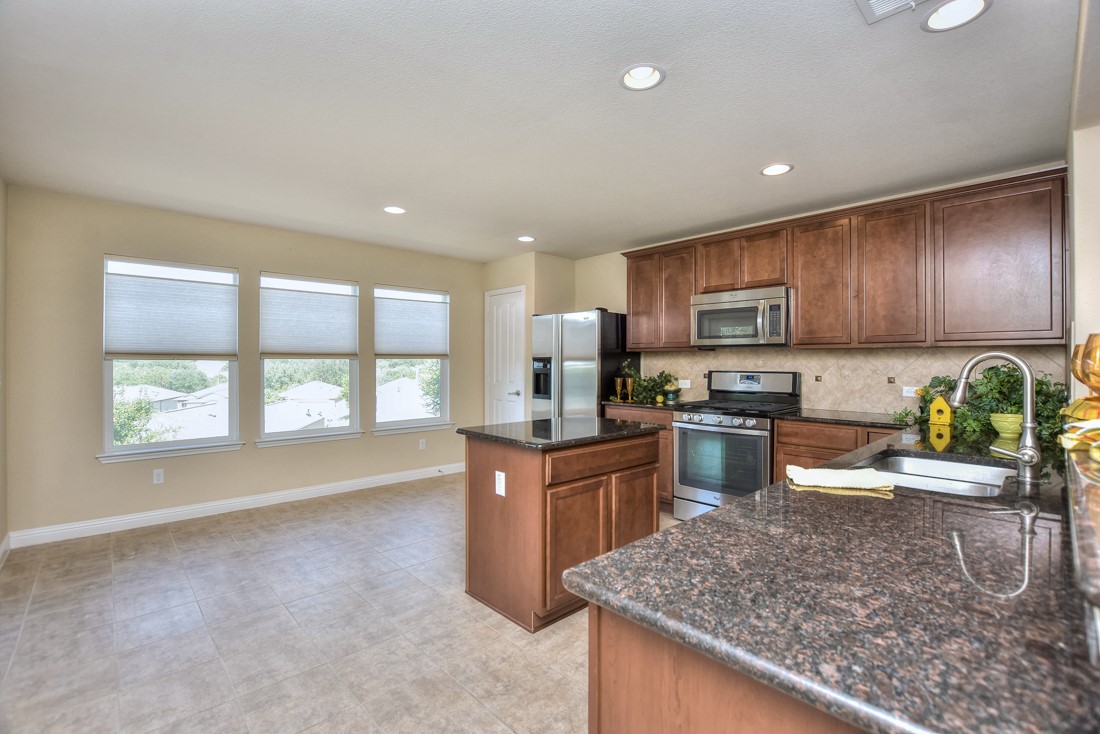 106 Kickapoo Creek Lane Georgetown, TX 78633 - Photo 14 of 33 a kitchen with granite countertop wooden cabinets a sink a stove a oven a dining table and chairs