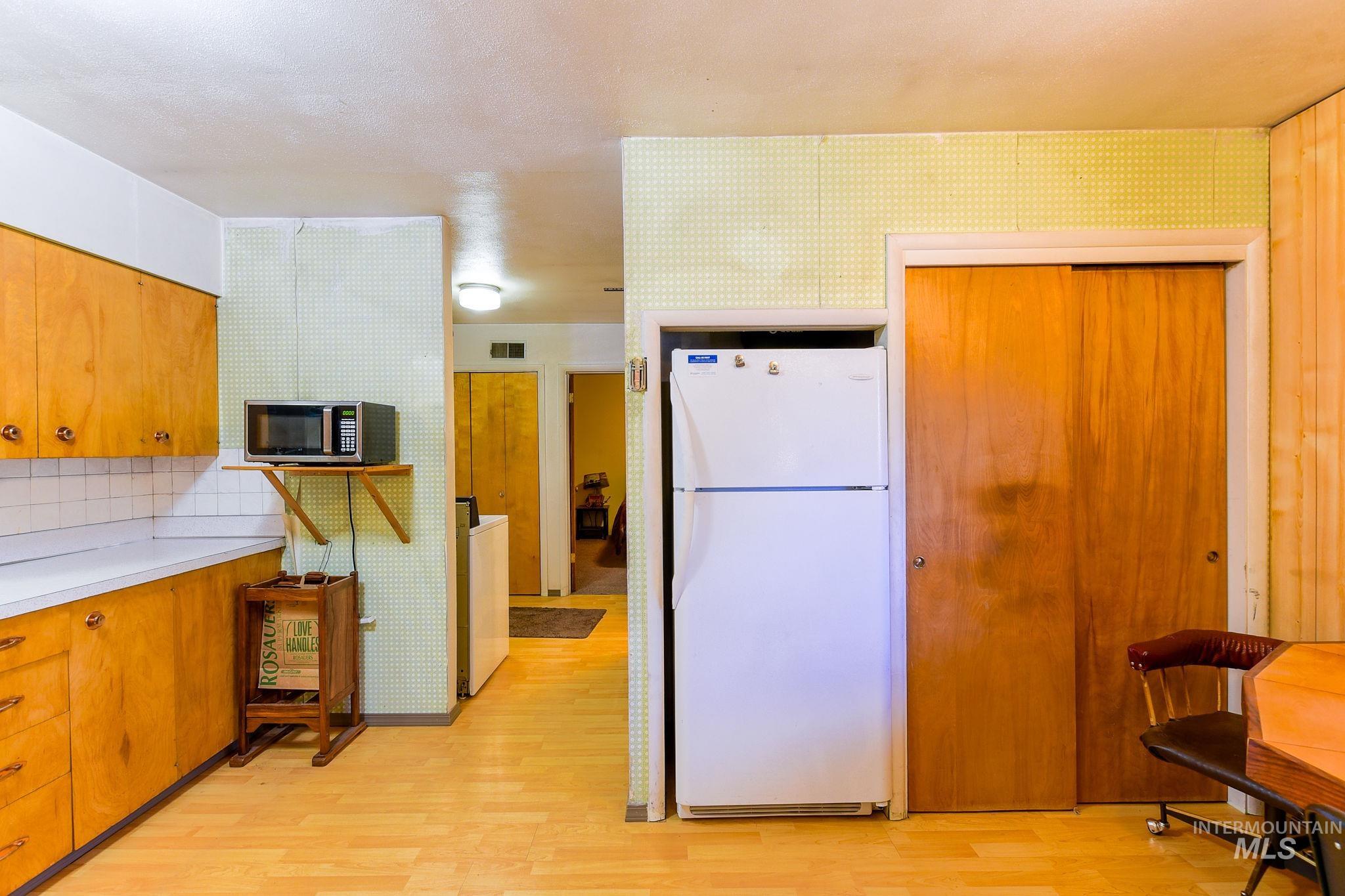 243 North Fir Street Genesee, ID 83832 - Photo 15 of 50 Kitchen with freestanding refrigerator, light wood-type flooring, light countertops, and brown cabinetry