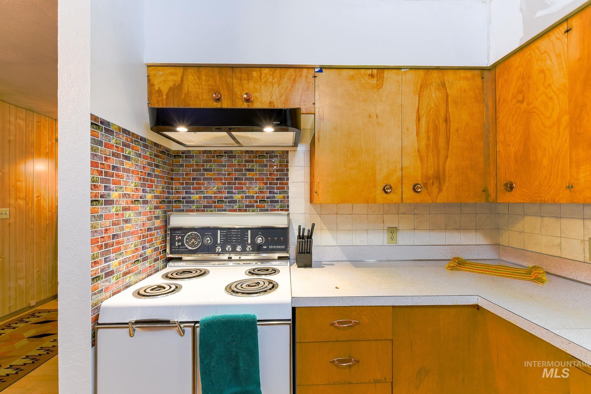 243 North Fir Street Genesee, ID 83832 - Photo 18 of 50 Kitchen with electric range, light countertops, ventilation hood, and brown cabinets