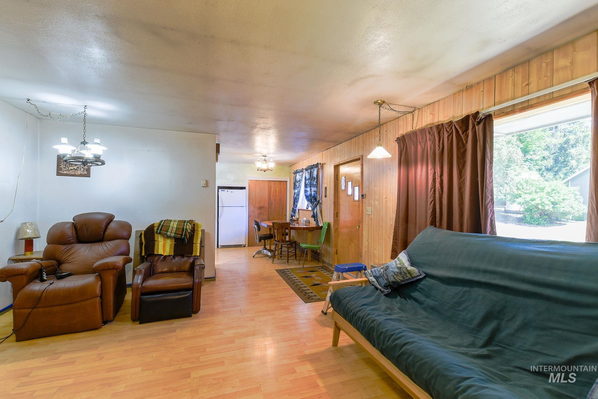 243 North Fir Street Genesee, ID 83832 - Photo 8 of 50 Living room featuring a chandelier, wood finished floors, and wooden walls