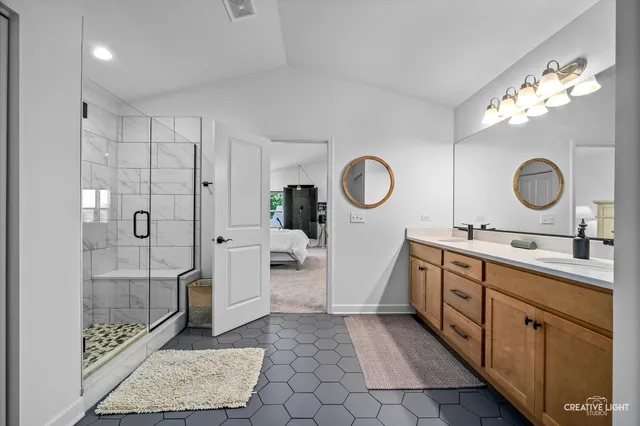 a spacious bathroom with a double vanity sink a mirror and a shower