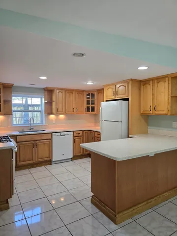 a kitchen with stainless steel appliances granite countertop a refrigerator a stove and a sink with wooden cabinets