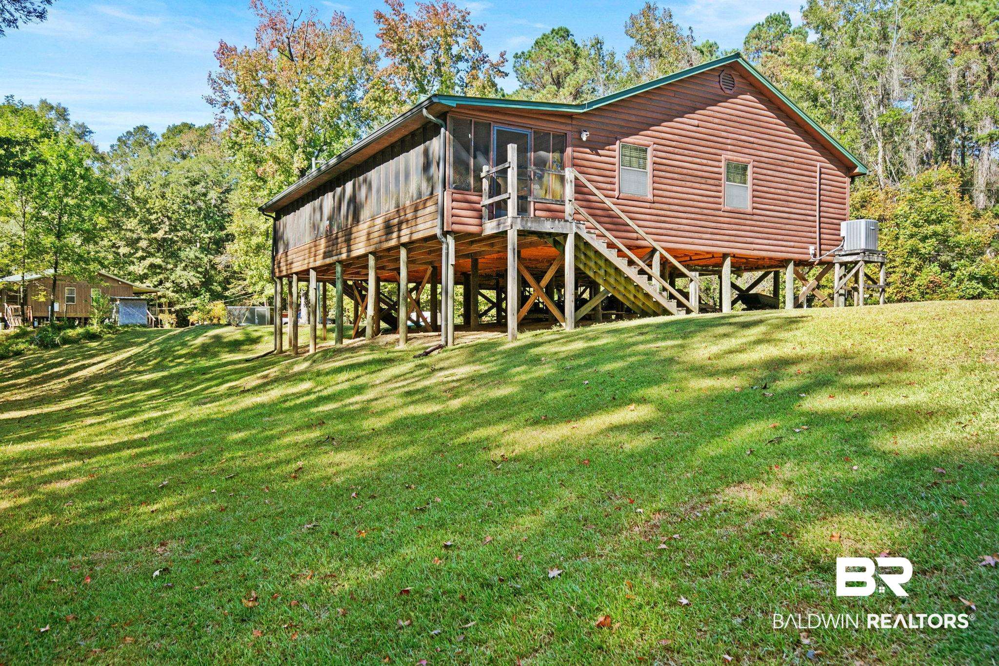 724 Rowell Lane Brewton, AL 36426 - Photo 4 of 40 Back of property featuring a sunroom, a yard, a deck, faux log siding, and stairway
