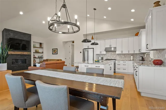 a kitchen with stainless steel appliances a dining table chairs and a refrigerator