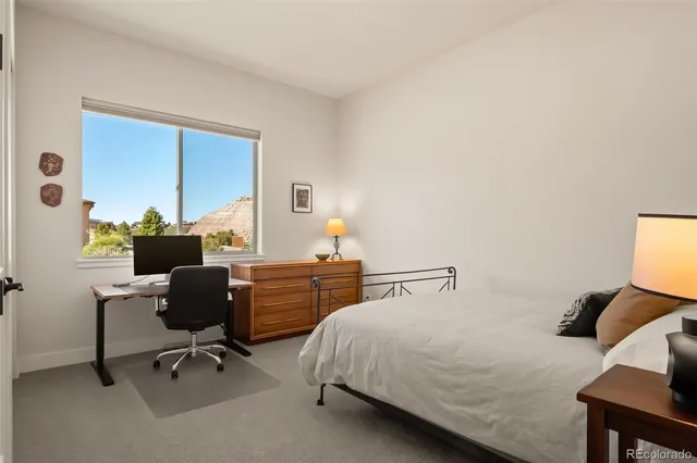 a bedroom with a bed a chair and a large window