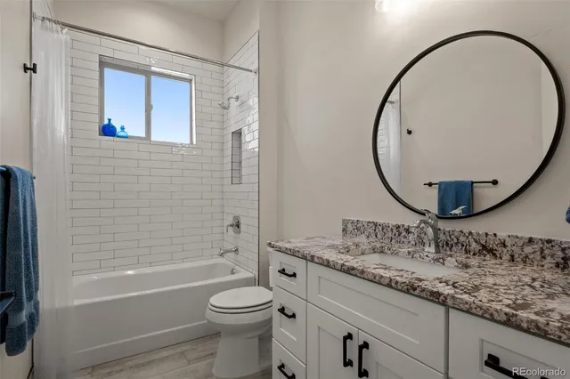 a bathroom with a granite countertop sink a toilet and a mirror