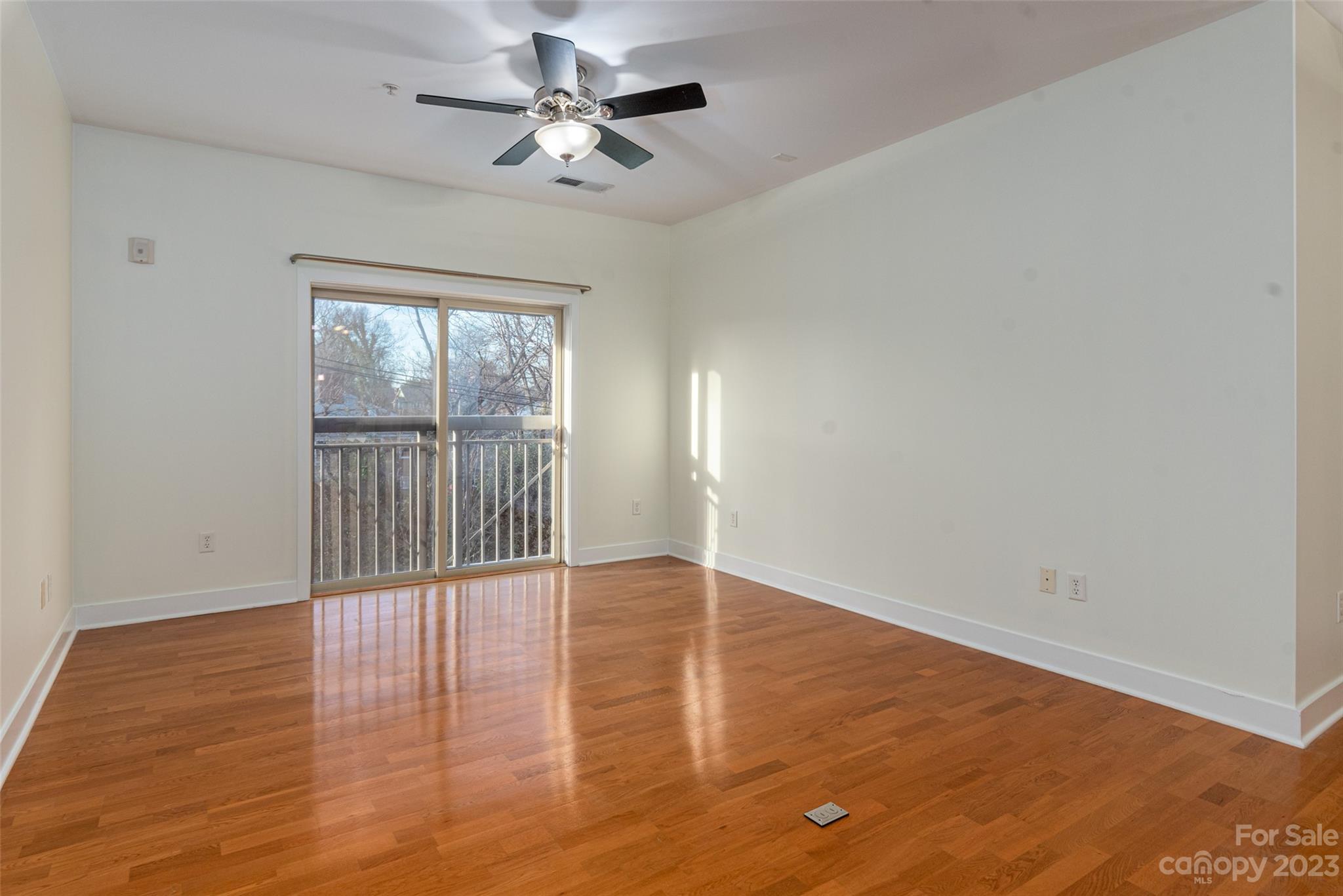 630 Calvert Street, Unit 307 Charlotte, NC 28208 - Photo 12 of 27 an empty room with wooden floor chandelier fan and windows