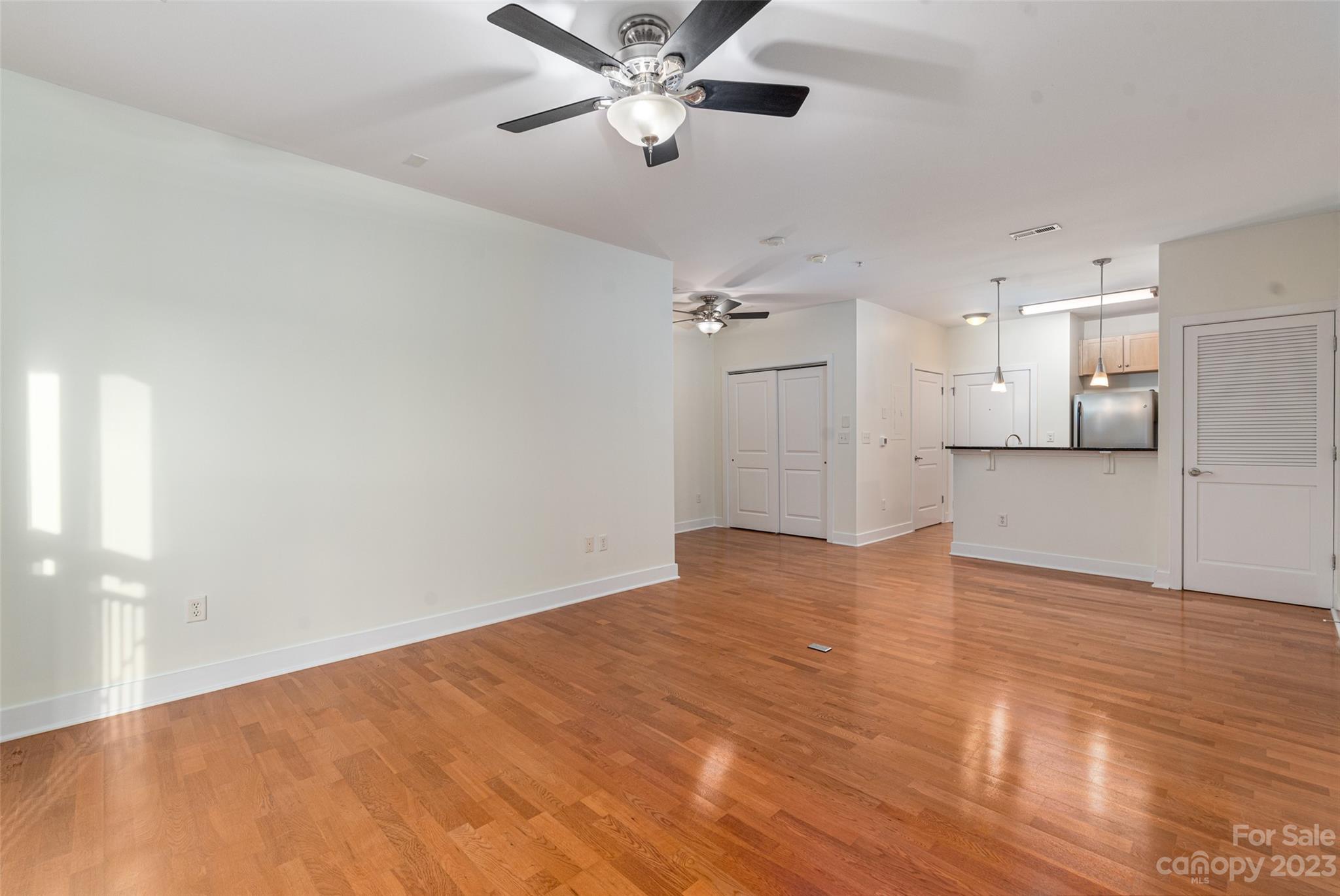 630 Calvert Street, Unit 307 Charlotte, NC 28208 - Photo 5 of 27 a view of empty room with wooden floor and ceiling fan