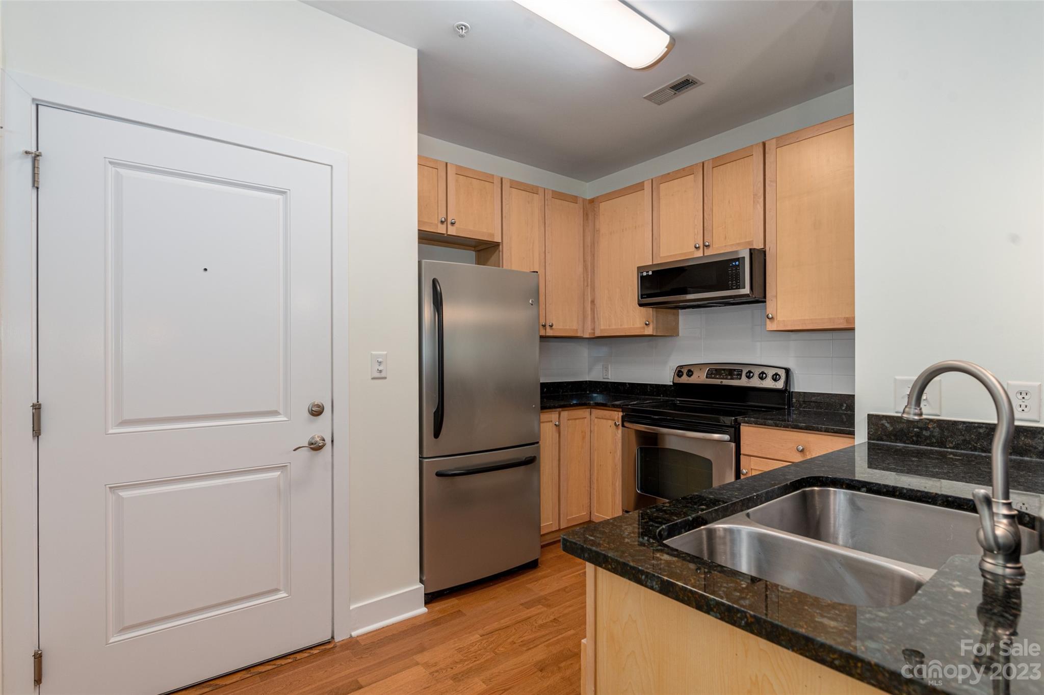 630 Calvert Street, Unit 307 Charlotte, NC 28208 - Photo 8 of 27 a kitchen with stainless steel appliances granite countertop a refrigerator sink and stove