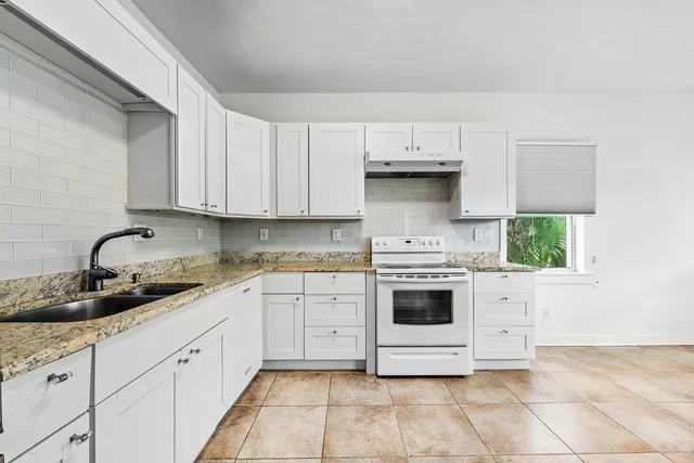 a kitchen with stainless steel appliances granite countertop white cabinets a stove a sink and dishwasher