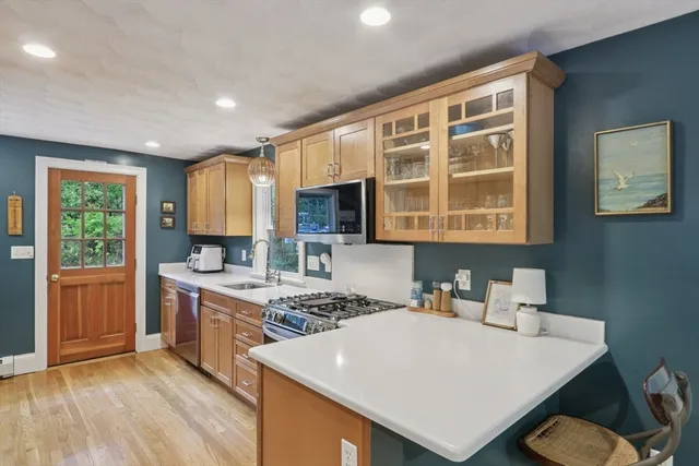 a kitchen with stainless steel appliances granite countertop a stove top oven a sink dishwasher a dining table and chairs with wooden floor