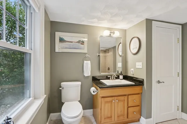 a bathroom with a granite countertop toilet sink and mirror
