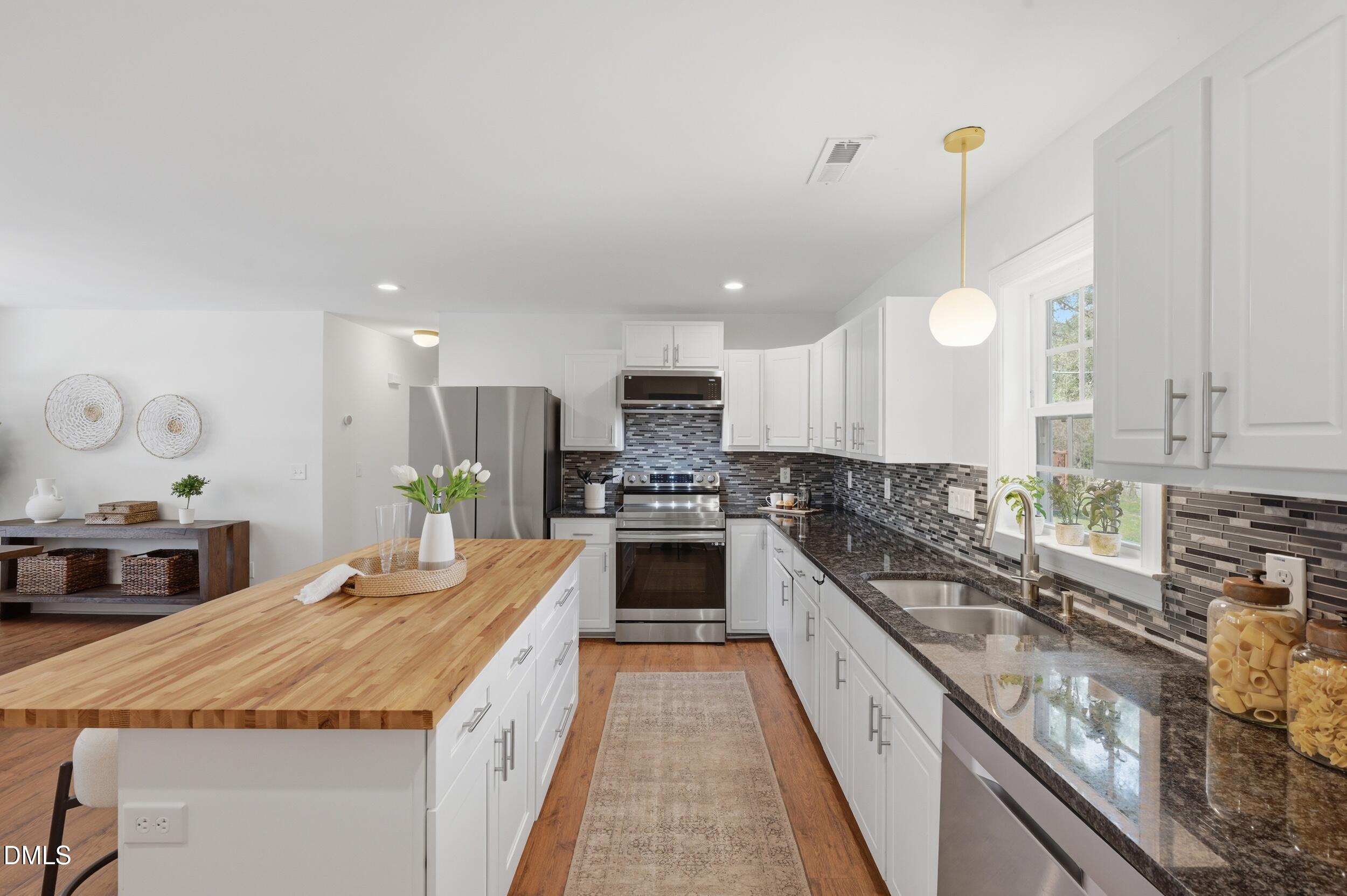 2301 Milburnie Road Raleigh, NC 27610 - Photo 2 of 23 a large kitchen with kitchen island a large counter top space a sink stainless steel appliances and cabinets