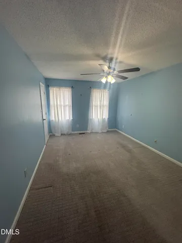 an empty room with windows and chandelier fan