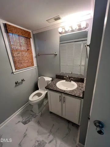 a bathroom with a granite countertop toilet a sink and a mirror