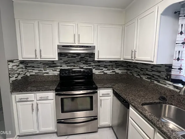 a kitchen with granite countertop white cabinets and stainless steel appliances