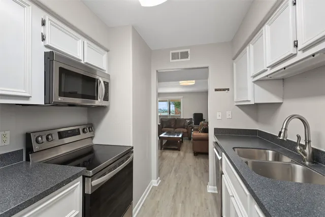 a kitchen with a sink dishwasher stove and microwave with wooden floor