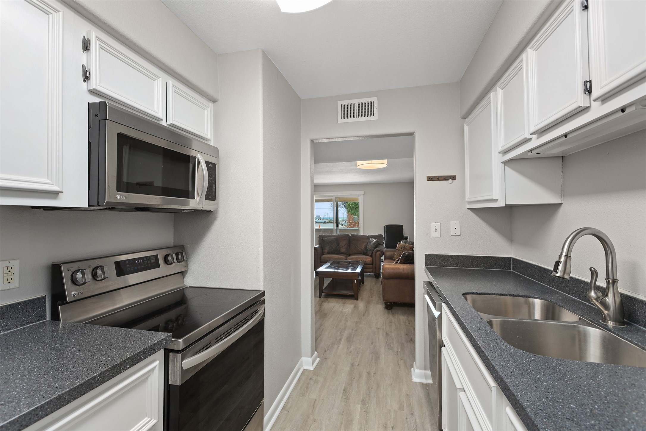 215 Postoffice Street, Unit 1208 Galveston, TX 77550 - Photo 6 of 19 a kitchen with a sink dishwasher stove and microwave with wooden floor