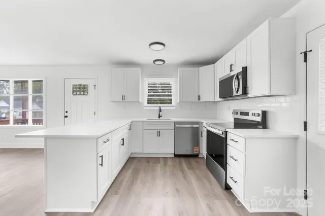 a kitchen with a sink cabinets stainless steel appliances and a window