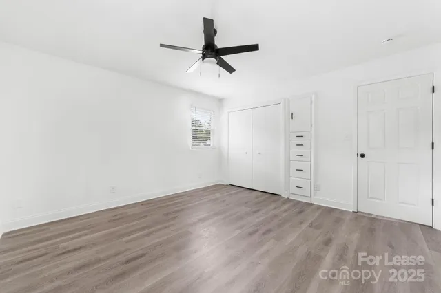 a view of a room with wooden floor and a ceiling fan