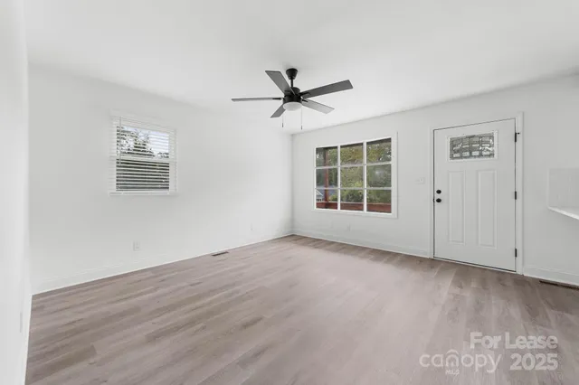 an empty room with wooden floor and ceiling fan