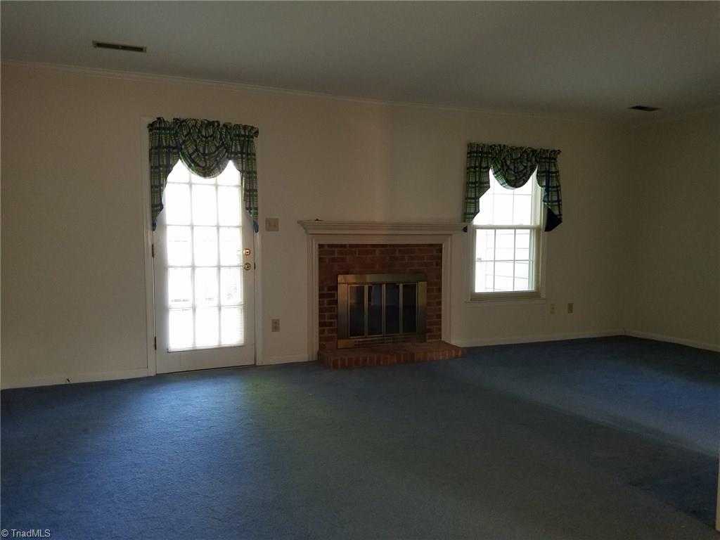 4917 B Tower Road Greensboro, NC 27410 - Photo 2 of 8 The Living Room features a wood burning fireplace with mantel and brick hearth and surround. Door leads to large private patio and secure storage area.