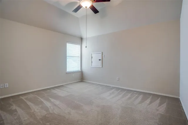 an empty room with chandelier fan and windows