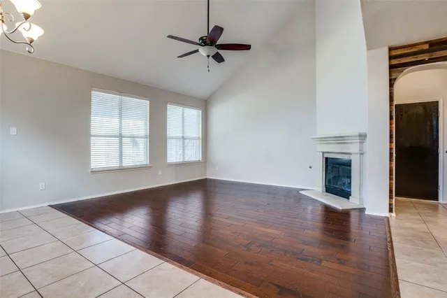 an empty room with wooden floor fireplace and windows