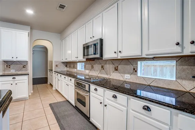 a kitchen with granite countertop white cabinets stainless steel appliances and a sink