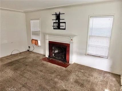 a view of an empty room with a fireplace and a window