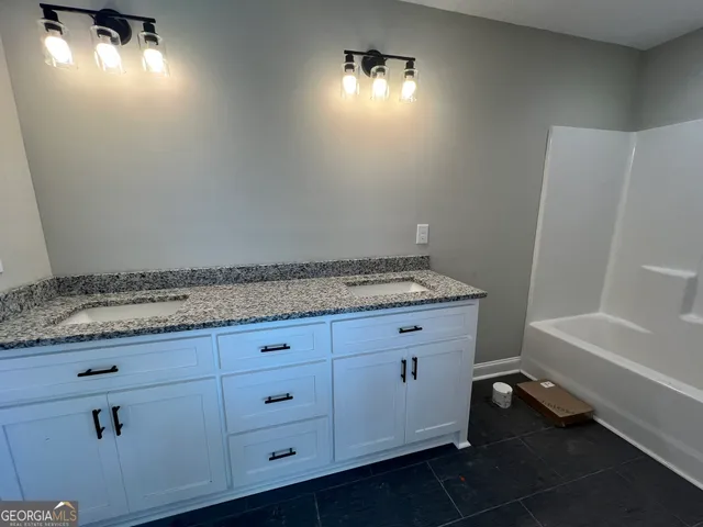 a bathroom with a granite countertop sink and washing machine