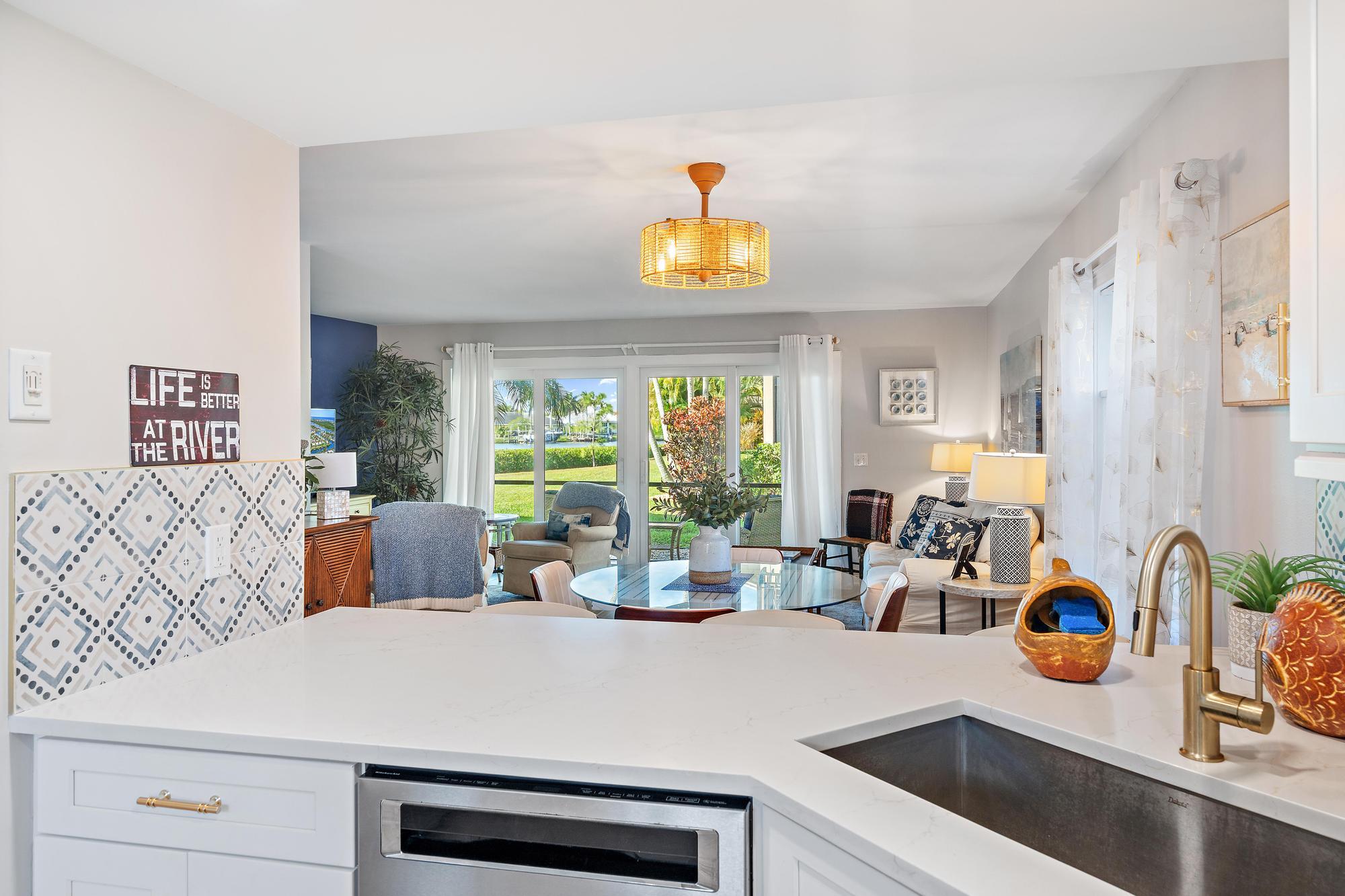 9170 Southeast Riverfront Terrace, Unit H Jupiter, FL 33469 - Photo 4 of 34 a view of a kitchen with kitchen island a stove a refrigerator a sink dishwasher with a dining table and chairs with wooden floor