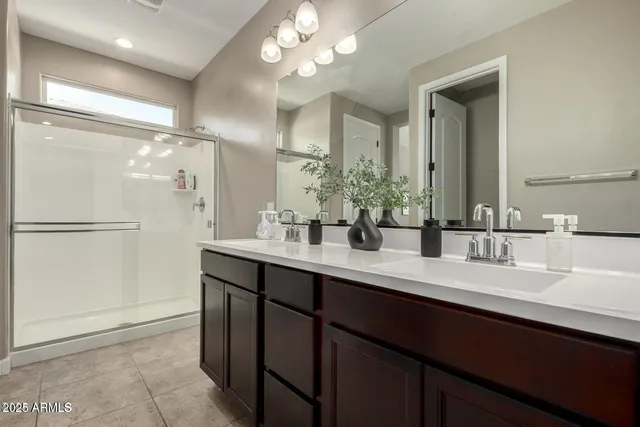 a bathroom with a double vanity sink a mirror and shower