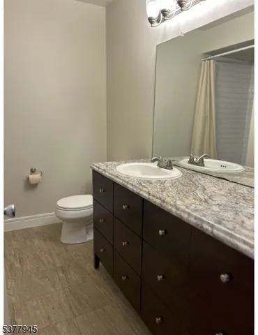a bathroom with a granite countertop sink a toilet and a mirror