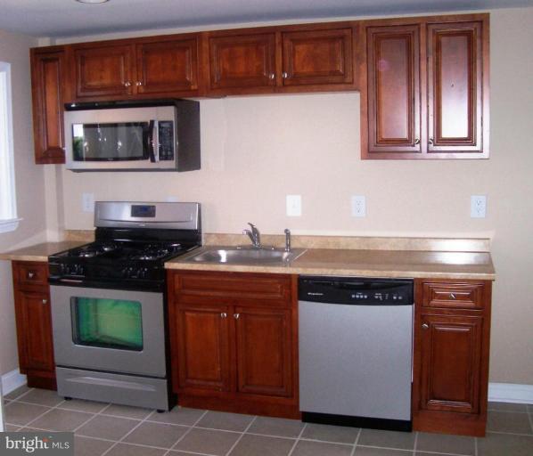 2462 Nevada Street Baltimore, MD 21230 - Photo 6 of 22 a kitchen with stainless steel appliances granite countertop a stove and a microwave