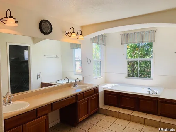 a spacious bathroom with a double vanity sink a large mirror and a bathtub