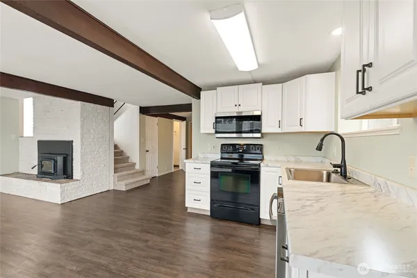 a kitchen with stainless steel appliances granite countertop a stove top oven a sink dishwasher and a refrigerator with wooden floor