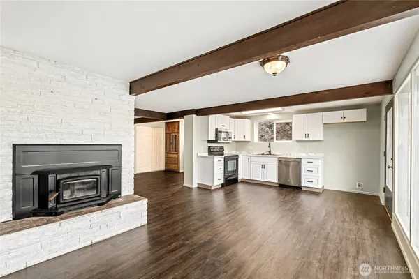 a kitchen with stainless steel appliances kitchen island granite countertop a stove a sink and white cabinets with wooden floor