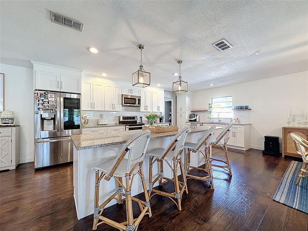 7813 River Ridge Drive Temple Terrace, FL 33637 - Photo 12 of 43 a kitchen with stainless steel appliances kitchen island granite countertop a table chairs refrigerator and sink