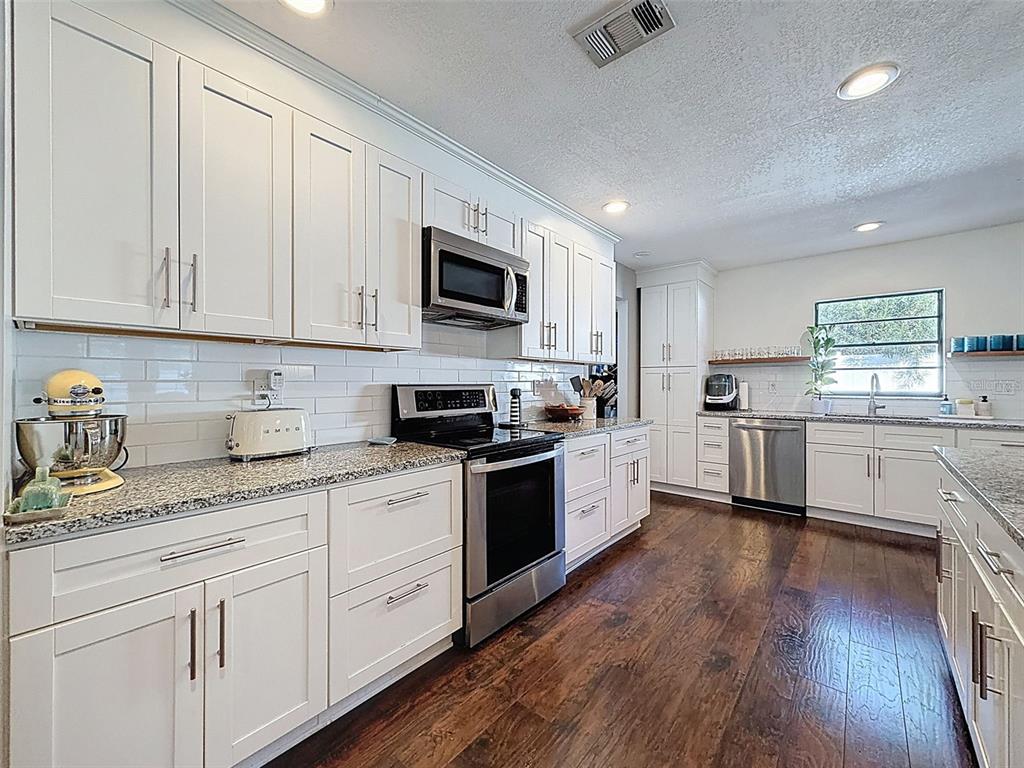 7813 River Ridge Drive Temple Terrace, FL 33637 - Photo 14 of 43 a kitchen with granite countertop white cabinets and white appliances