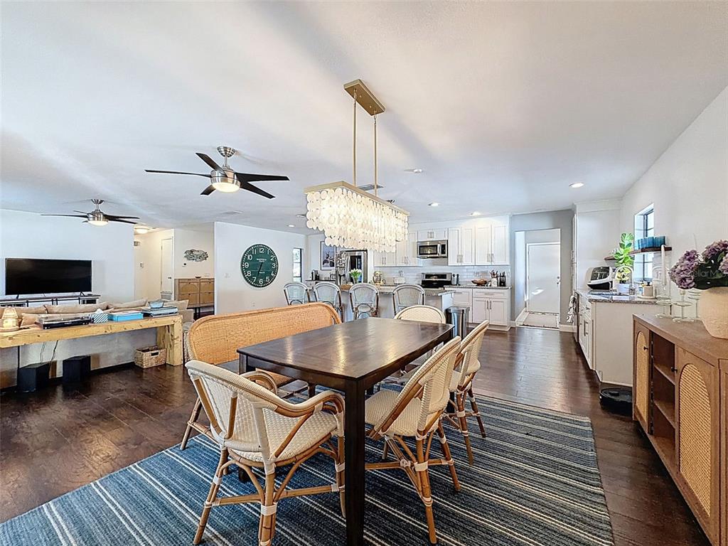 7813 River Ridge Drive Temple Terrace, FL 33637 - Photo 18 of 43 a dining room with furniture wooden floor a rug a flat screen tv a painting and a chandelier