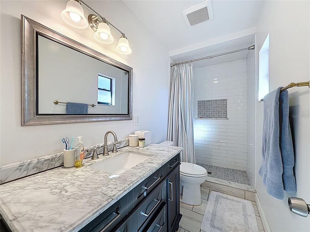 7813 River Ridge Drive Temple Terrace, FL 33637 - Photo 22 of 43 a bathroom with a granite countertop sink a toilet a mirror and shower