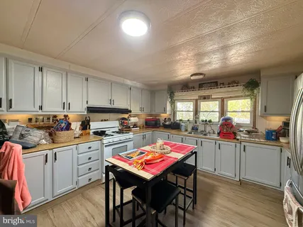 a kitchen with a stove a sink dishwasher a dining table and chairs with wooden floor